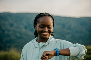 Fitness Tracking in Motion: a black jogger effortlessly glides along a forest path while her...