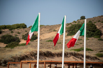 banderas italianas en la costa verde Cerdeña Italia  - obrazy, fototapety, plakaty