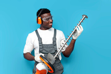 garden worker in uniform holding electric brush cutter on blue isolated background
