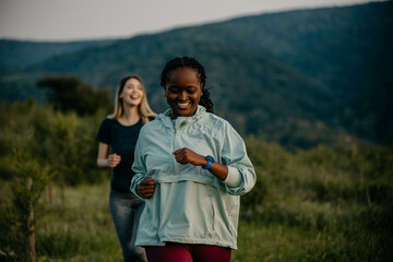 Monitoring Performance: With the sun illuminating their path, diverse joggers maintain their pace while monitoring their heart rate on their smartwatches, ensuring an optimized workout experience.