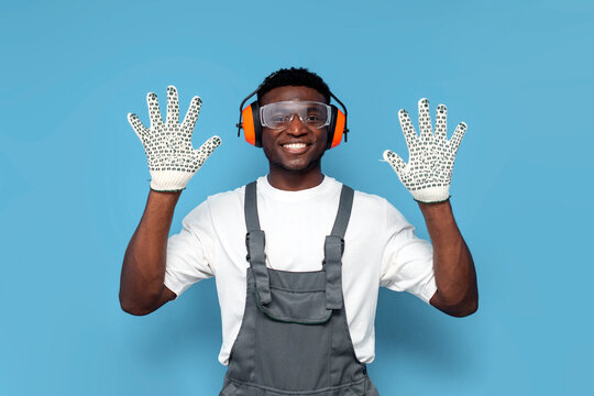 I give up. handyman in uniform and gloves shows his palms and raises his hands up on blue background