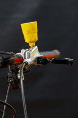 Bleeding the brake system of a mountain bike with a funnel. Bicycle repair. A mountain bike handlebar and modern disc hydraulic brakes on a black background.