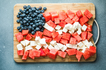 Patriotic salad idea with blueberries, feta and watermelon in the shape of American flag on gray...