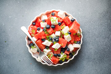 Summer salad with watermelon, feta cheese and mint on a gray background. Vegan, European food.