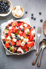 Summer salad with watermelon, feta cheese and blueberry on a gray background. Vegan, European food.
