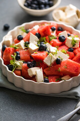 Summer salad with watermelon, feta cheese and blueberry on a gray background. Vegan, European food.