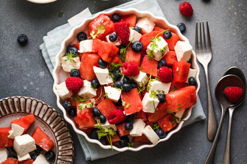 Summer salad with watermelon, feta cheese and blueberry on a gray background. Vegan, European food.