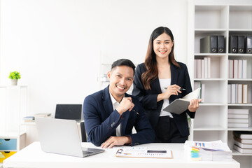 Smart and professional male manager working with his female assistant. check financial reports Analyze financial data with graph papers and laptop with desk.