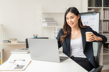 Fototapeta premium Asian female accountant doing payroll of company employees with statistics and analytical research concept with financial graph working on laptop.