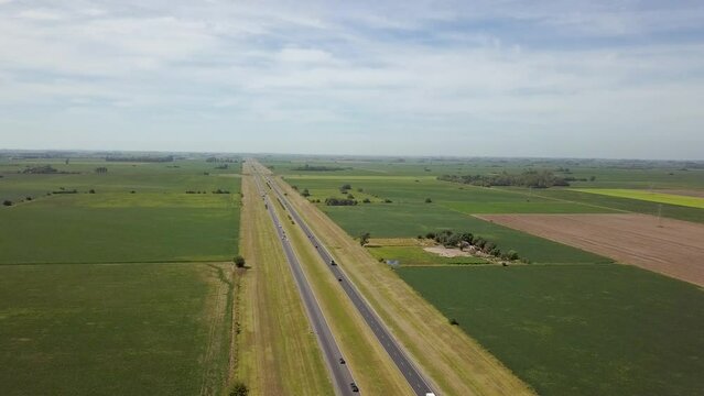 Drone flight over highway with traffic crossing over soybean fields