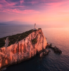 Lighthouse on the mountain peak at colorful sunset in summer. Aerial view. Beautiful lighthouse on...