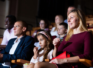 Young woman spending time with her family, watching together interesting movie in picture theater