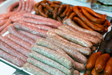Different types of meat sausages laid out on counter in butcher shop..