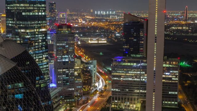 Skyline view of the high-rise buildings on busy curved road in Dubai aerial during all night timelapse, UAE. Illuminated office skyscrapers in International Financial Centre from above