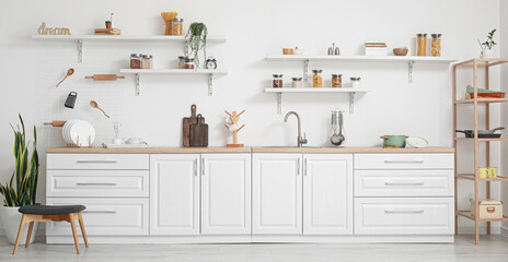 Interior of light kitchen with white counters and utensils