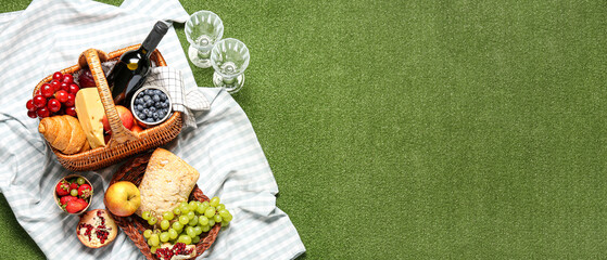 Tasty food for picnic with wine on plaid in green park. Banner for design