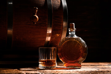 Barrel with bottle and glass of rum on wooden table
