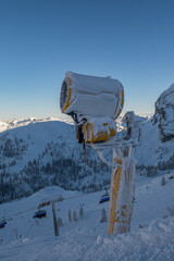 Naklejka na ściany i meble Snow cannon, snow powder making on the ski slope Nassfeld, Austria, with Backlit splashing. January 2022