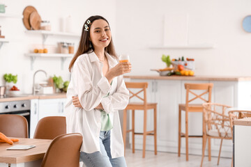 Fototapeta na wymiar Young woman with glass of vegetable juice in kitchen