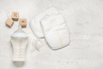 Fototapeta na wymiar Bottle of milk for baby and accessories on white textured background