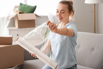 Young woman with roll of stretch wrap at home