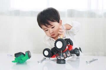 A 2-year-old boy is diligently repairing toys under the concept of training and learning for children.
