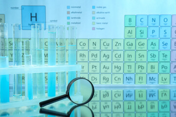 Magnifying glass and test tubes in rack on mirror surface against periodic table of chemical...