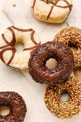Board with sweet chocolate donuts on light grunge background