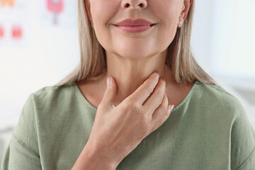 Endocrine system. Senior woman doing thyroid self examination indoors, closeup