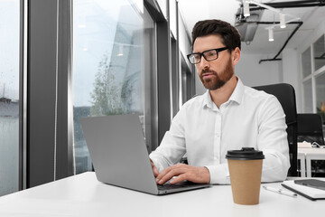 Man working on laptop at white desk in office. Space for text