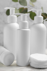 Different face cleansing products and cotton pads on marble table