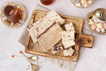 Pieces of tasty marble halva and glass with Turkish tea on white background