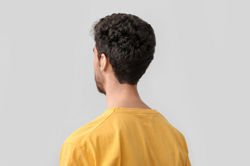 Young brunette man with stylish hairdo on light background, closeup