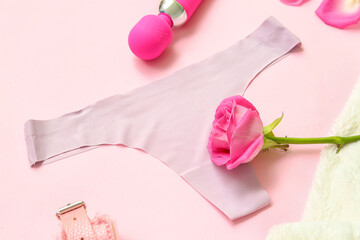 Female panties, rose flower and vibrator on pink background, closeup