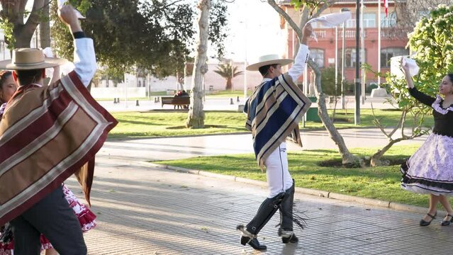 mixed group of four people dressed as huaso dancing cueca in the town square	