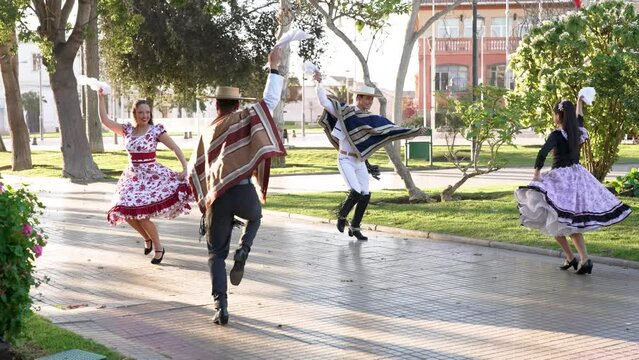 mixed group of four people dressed as huaso dancing cueca in the town square