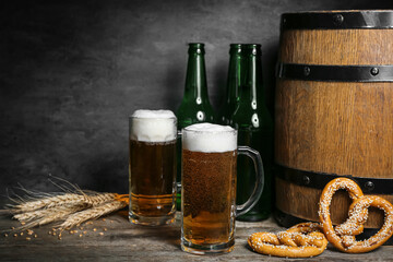 Mugs of cold beer, pretzels and wooden barrel on table. Oktoberfest celebration