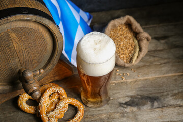 Glass of cold beer, pretzels and barrel on wooden background. Oktoberfest celebration