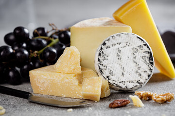 Piece of parmesan cheese close up and different types of cheeses in the background.