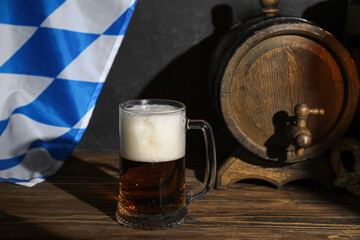 Mug of cold beer and wooden barrel on table. Oktoberfest celebration