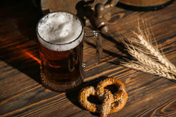 Mug of cold beer and pretzel on wooden background. Oktoberfest celebration