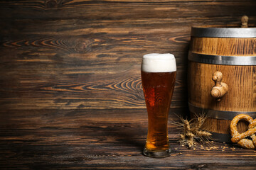 Glass of cold beer and barrel on wooden background. Oktoberfest celebration