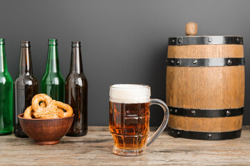 Mug of cold beer, pretzels and wooden barrel on table. Oktoberfest celebration