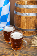 Mugs of cold beer and wooden barrel on table. Oktoberfest celebration