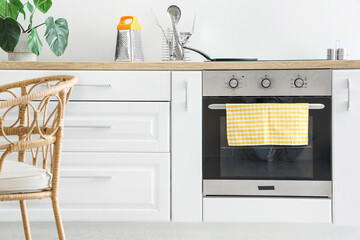 Oven with electric stove and frying pan near white wall in kitchen