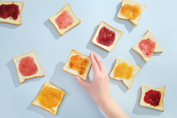 Female hand and delicious toasts with different jams on light background