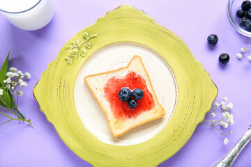 Plate of tasty toast with jam and blueberry on color background, closeup