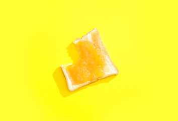 Bitten toast with sweet jam on yellow background