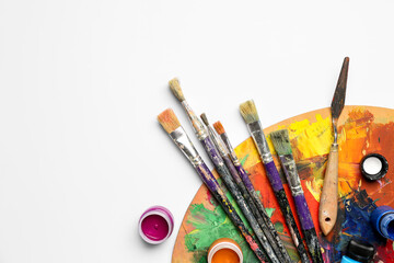 Obraz premium Wooden palette with different paints and brushes isolated on white background