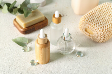 Fototapeta na wymiar Cosmetic dropper bottles with soap and sponge on light background